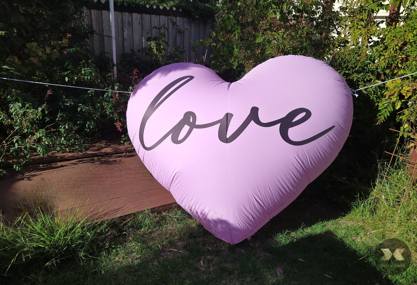 Large lavender purple inflatable heart backdrop balloon with black cursive Love text for garden party and event rental in Melbourne